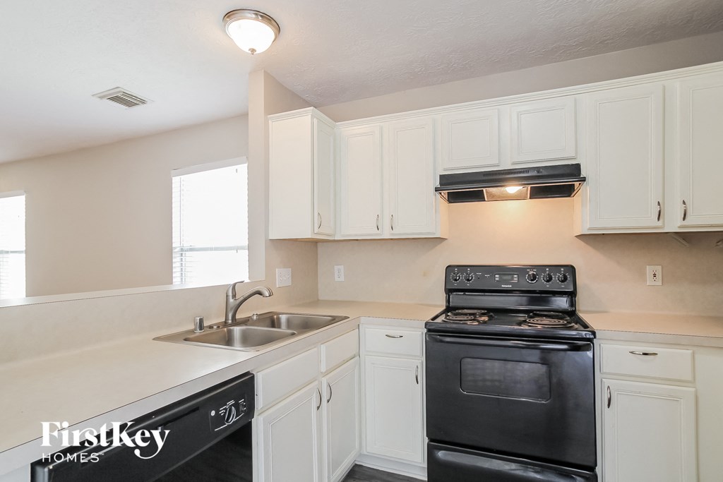 a kitchen with white cabinets and black appliances and a sink
