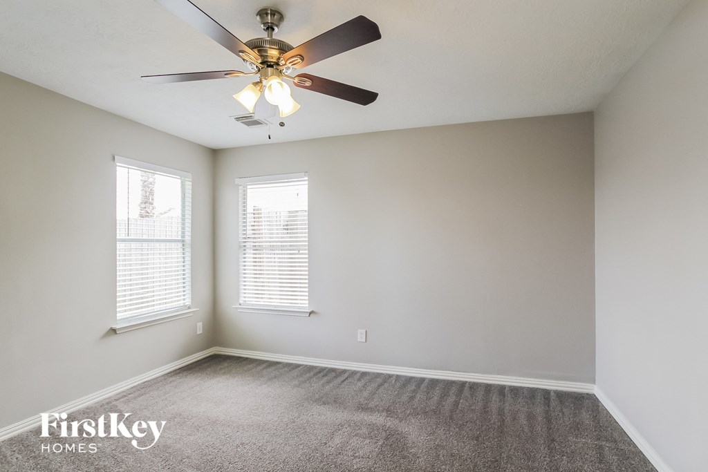 an empty room with a ceiling fan and two windows