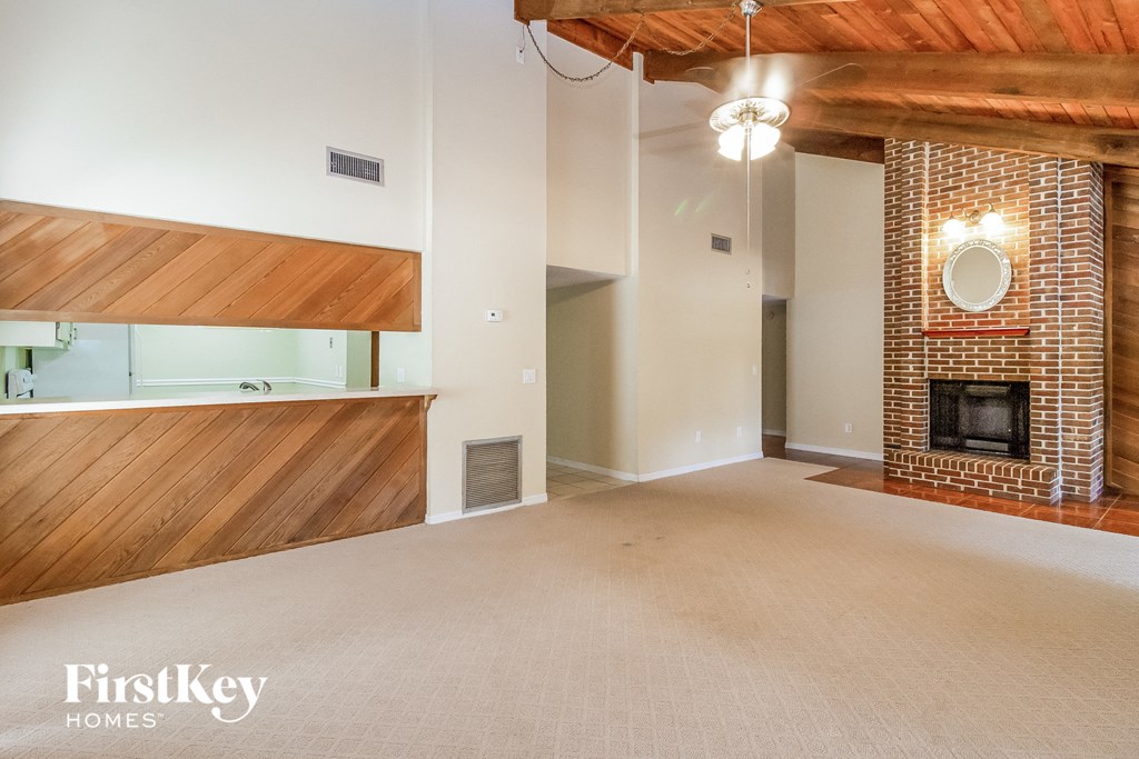 an empty living room with a brick fireplace and a wood floor