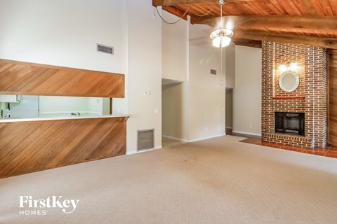 an empty living room with a brick fireplace and a wood floor