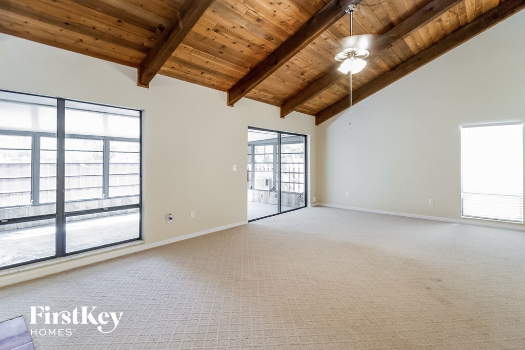 an empty living room with exposed wood ceilings and a large window