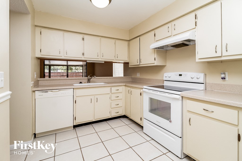 an empty kitchen with white appliances and white cabinets