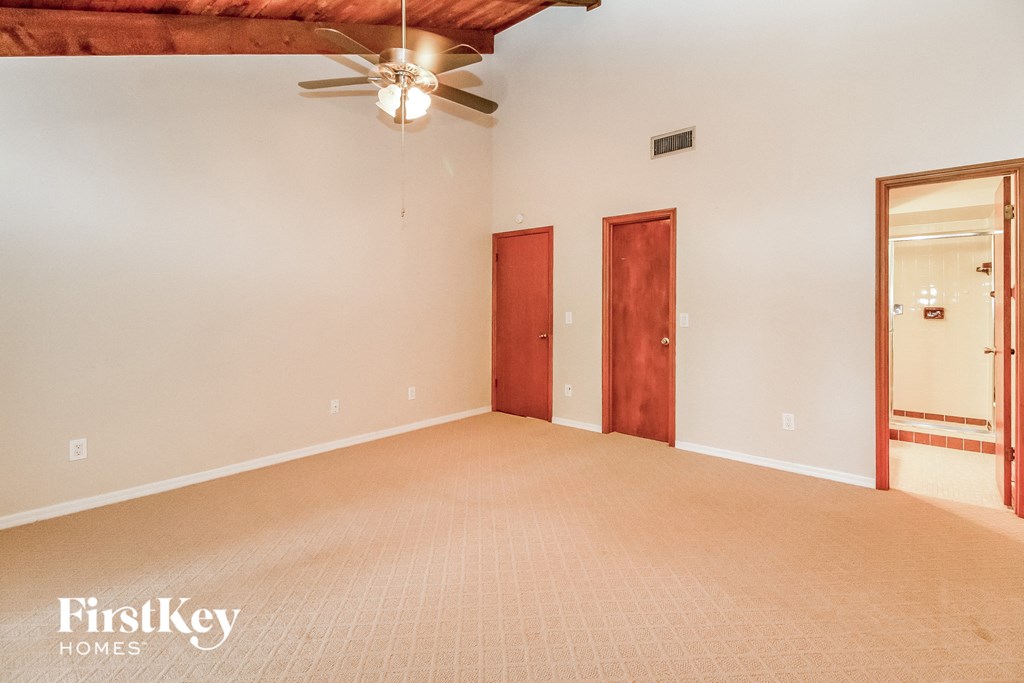 an empty living room with a ceiling fan and a closet
