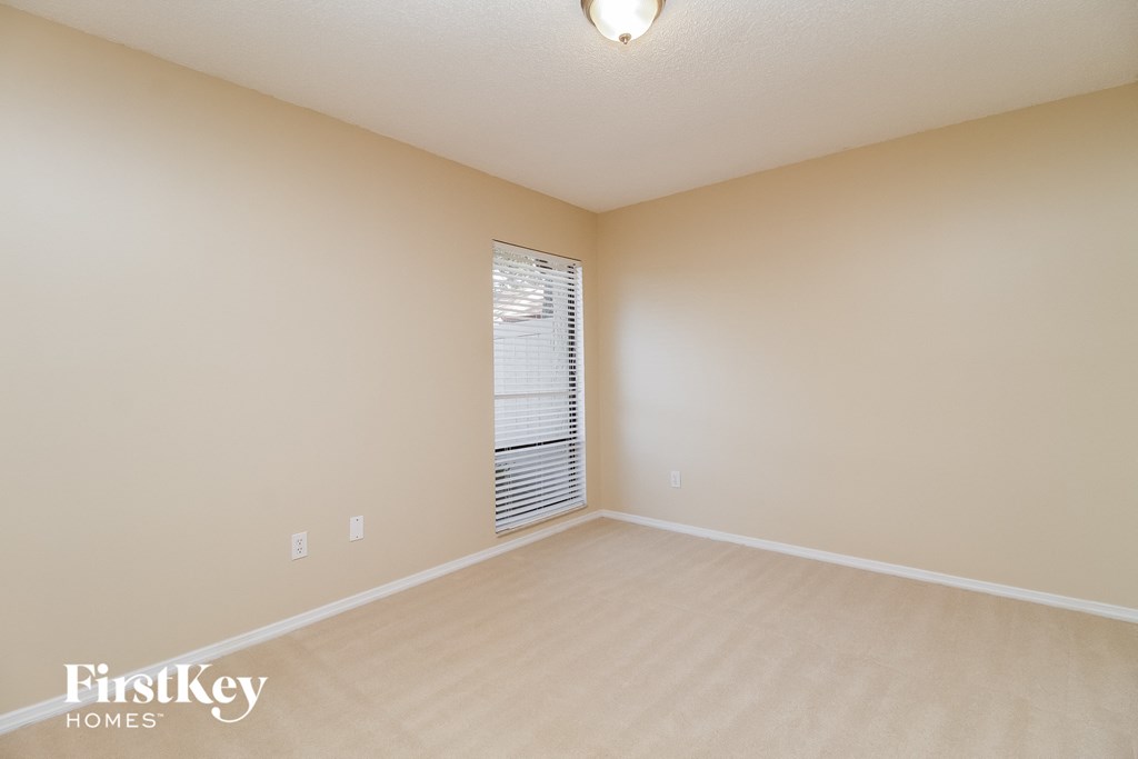 a spacious living room with beige carpet and a window