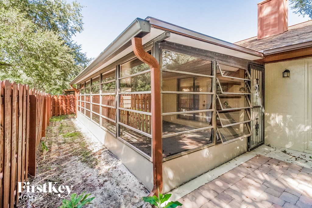 a patio with a fence and a house with glass windows