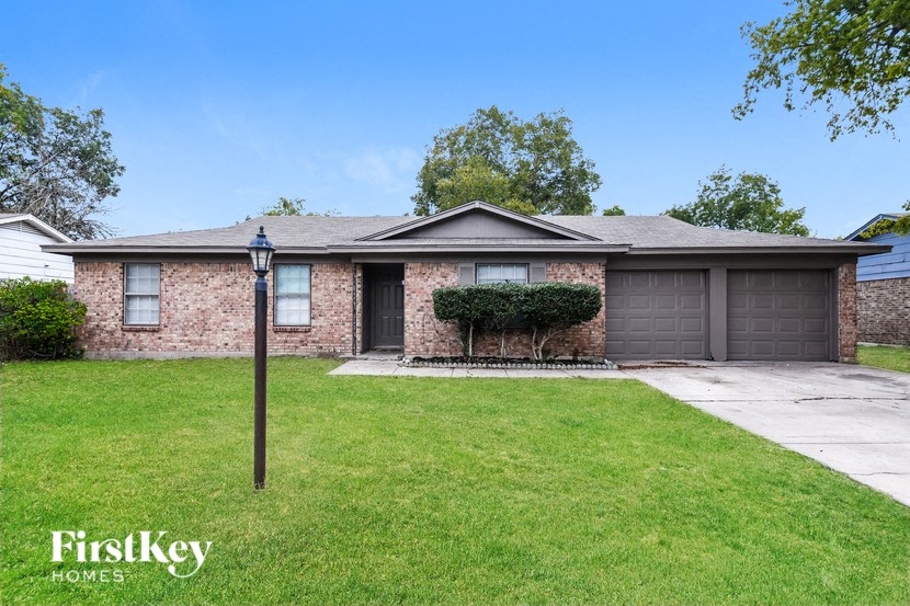 a small brick house with a lawn and a driveway