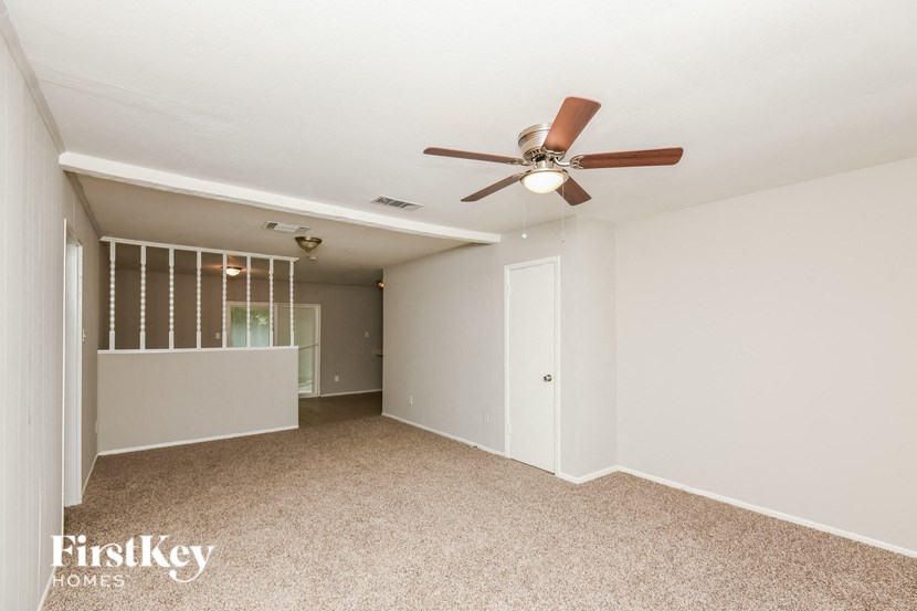 a living room with a ceiling fan and a mirrored closet
