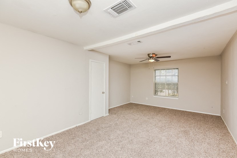 an empty living room with a ceiling fan and a window
