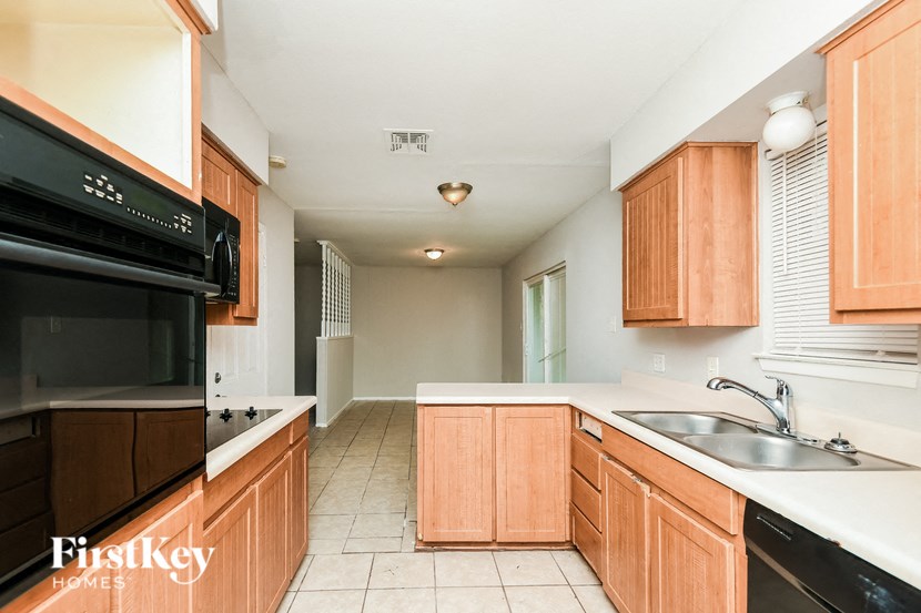a kitchen with wood cabinets and black appliances and a sink