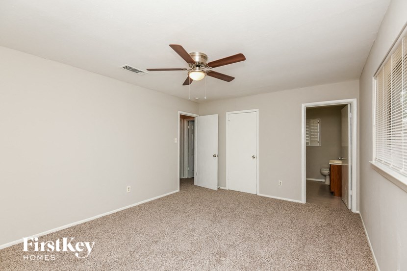 a living room with a ceiling fan and a door to a bathroom