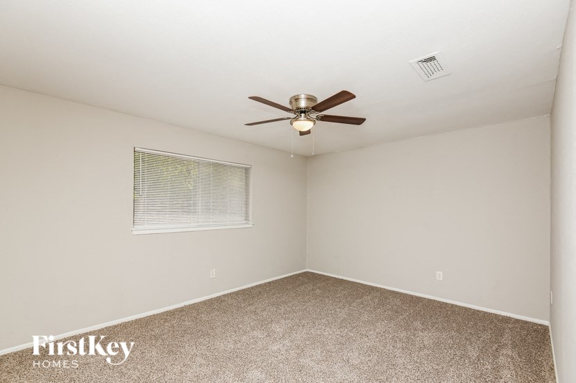 an empty room with a ceiling fan and a window