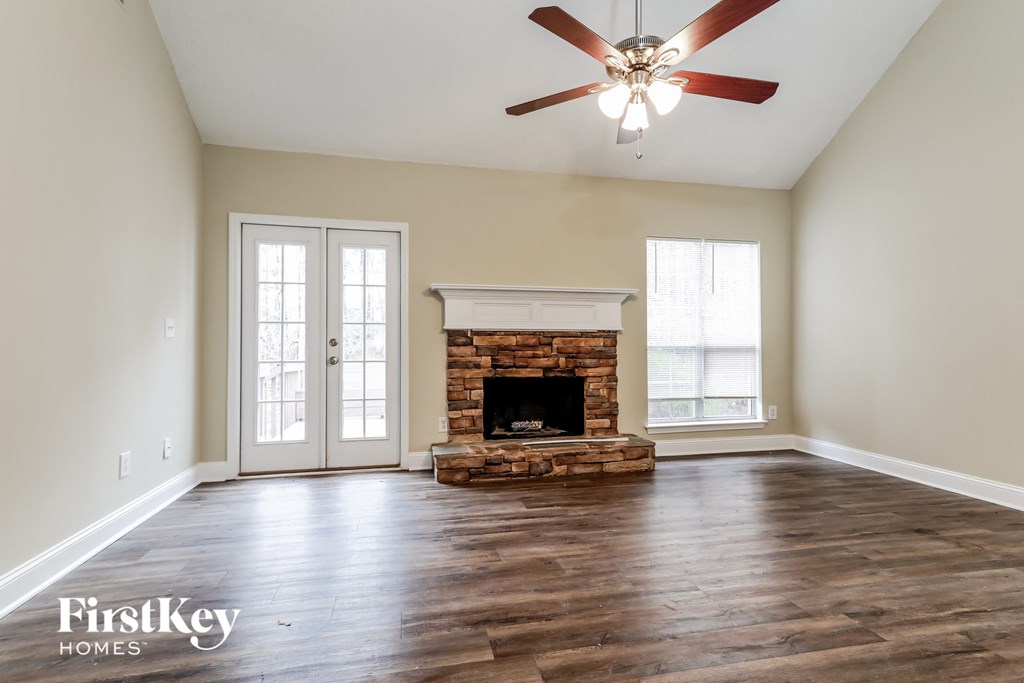 A spacious room with a fireplace and a ceiling fan.