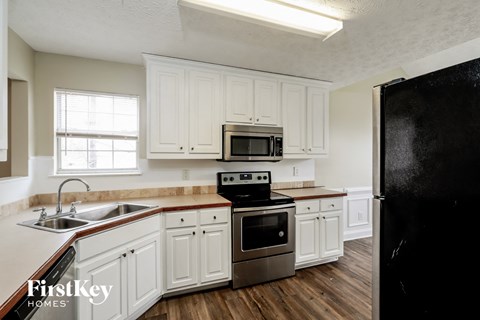 A kitchen with white cabinets and a black refrigerator.