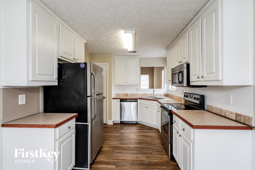 A kitchen with white cabinets and a black fridge.