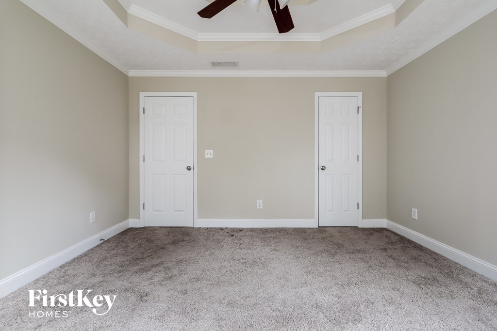 A room with two white doors and a ceiling fan.