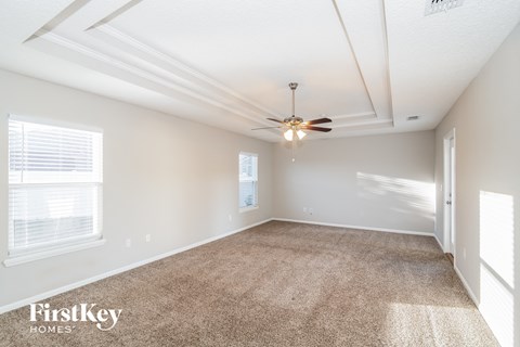 a spacious living room with carpet and a ceiling fan