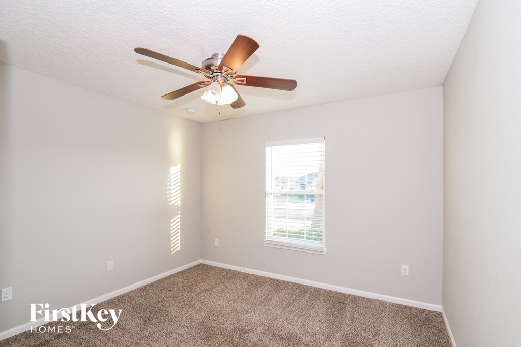 a bedroom with a ceiling fan and a carpet