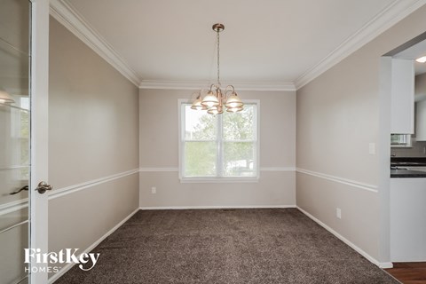 an empty dining room with a chandelier and a window