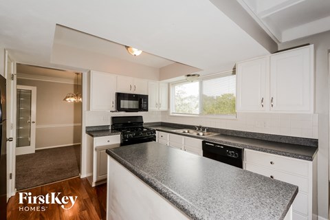 an updated kitchen with granite counter tops and white cabinets