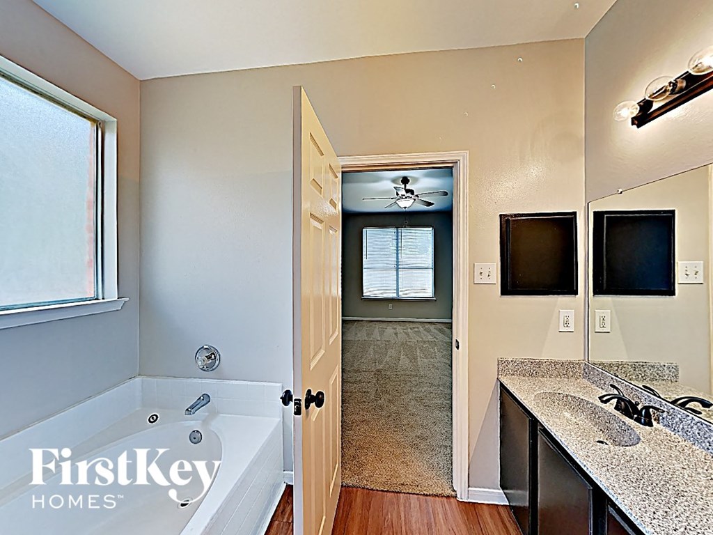 a bathroom with a tub and a sink and a door to a hallway