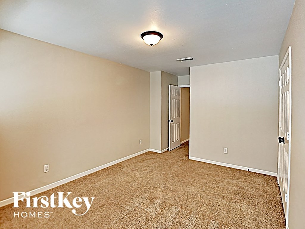 an empty living room with carpet and a door to a hallway