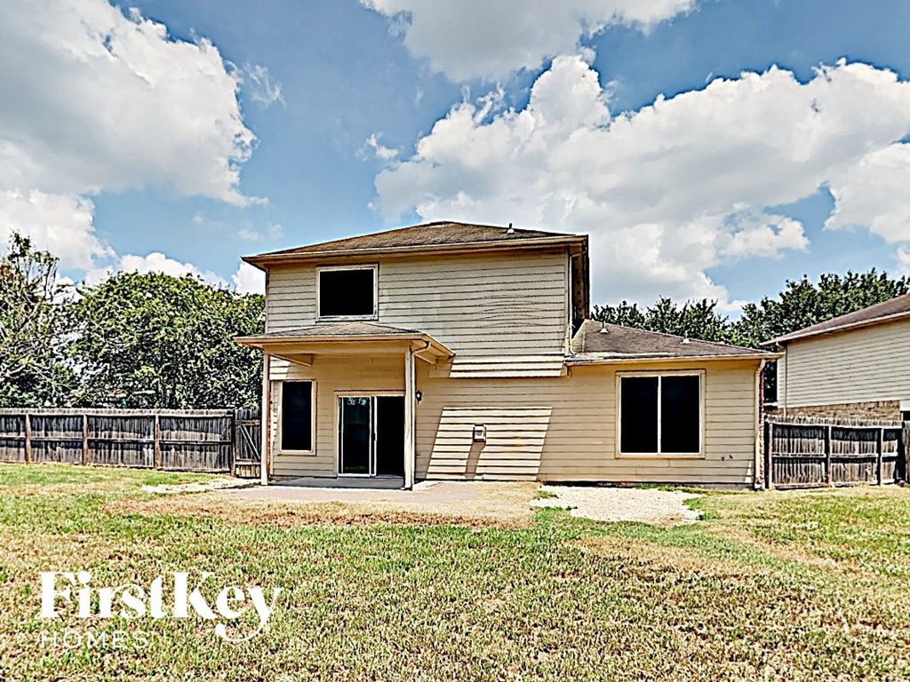 the front of a house with a yard and a fence