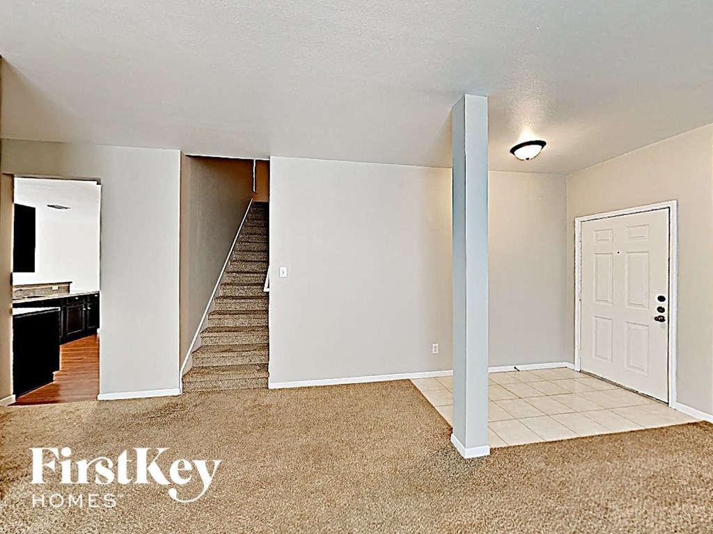 an empty living room with a staircase and a white door