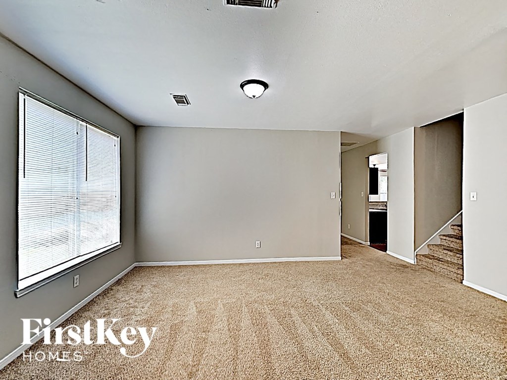 an empty living room with carpet and a large window