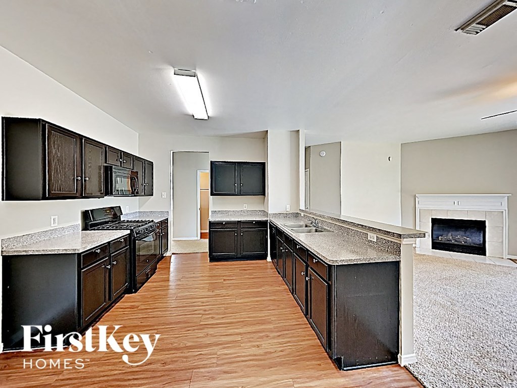 an empty kitchen with black cabinets and a fireplace