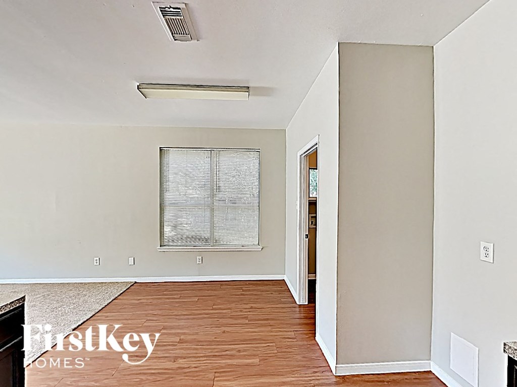 an empty living room with wood flooring and a window