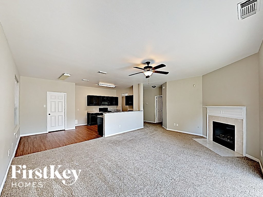 an empty living room with a fireplace and a kitchen