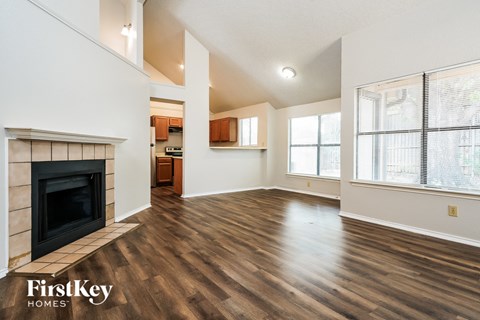A spacious living room with wood flooring and a fireplace.