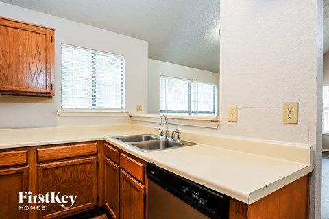 A kitchen with wooden cabinets and a black dishwasher.