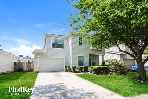A house with a driveway and a tree in front of it.
