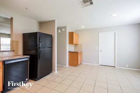 A kitchen with a black fridge and wooden cabinets.