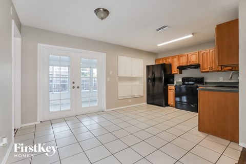 a kitchen with black appliances and wooden cabinets and white tiled floors