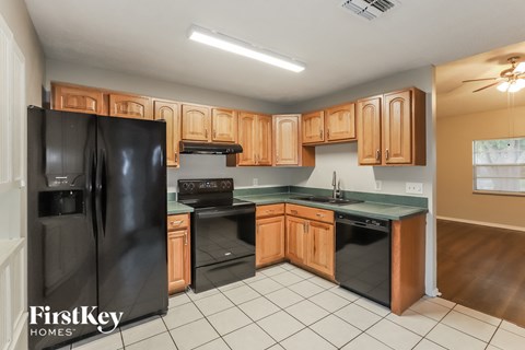 a kitchen with black appliances and wooden cabinets and white tiles