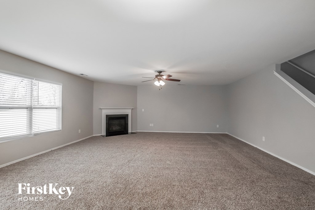 A spacious room with a fireplace and a ceiling fan.