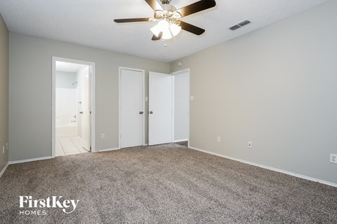 a spacious living room with carpet and a ceiling fan