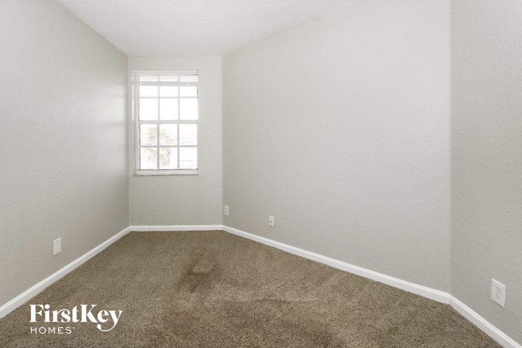 a carpeted room with a window and white walls