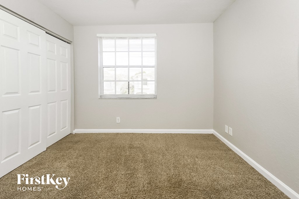 a carpeted room with a window and a white door