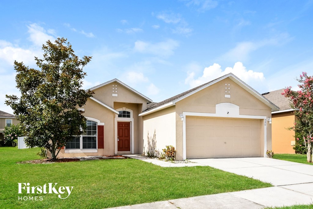 a beige house with a garage door and a lawn