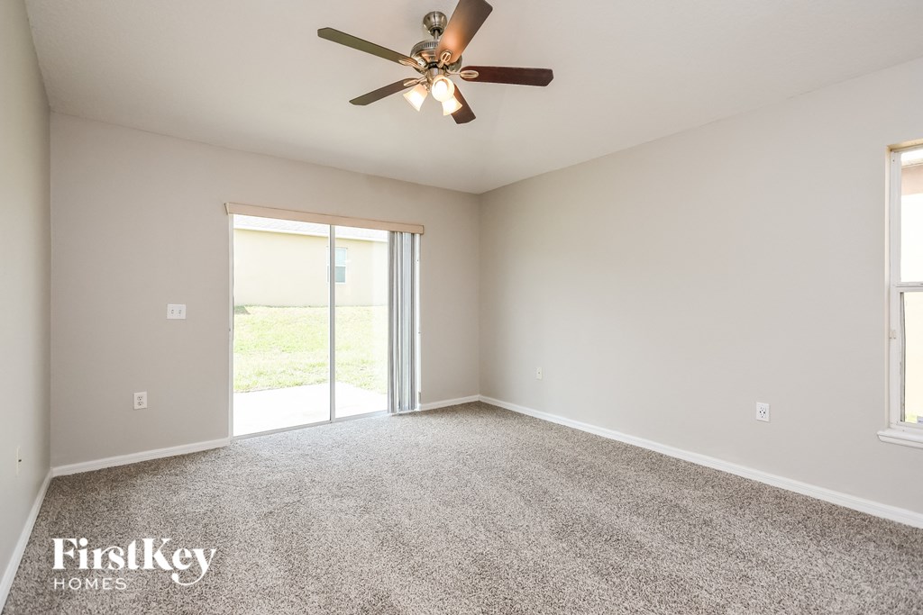 the spacious living room with ceiling fan and carpet