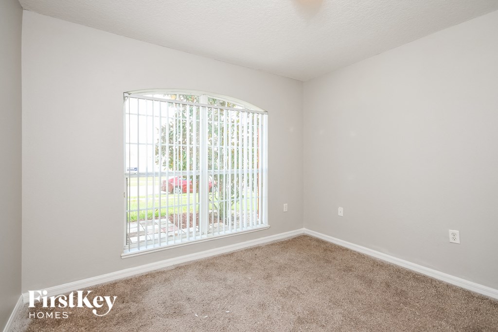 a spacious living room with a large window and carpet