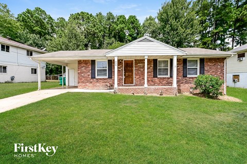 a small brick house with a lawn and a porch