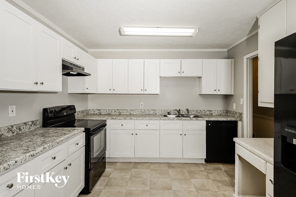 a kitchen with white cabinets and black appliances