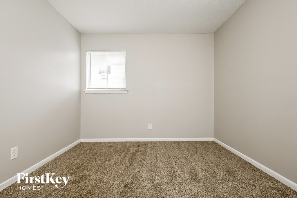 a bedroom with white walls and carpet and a window