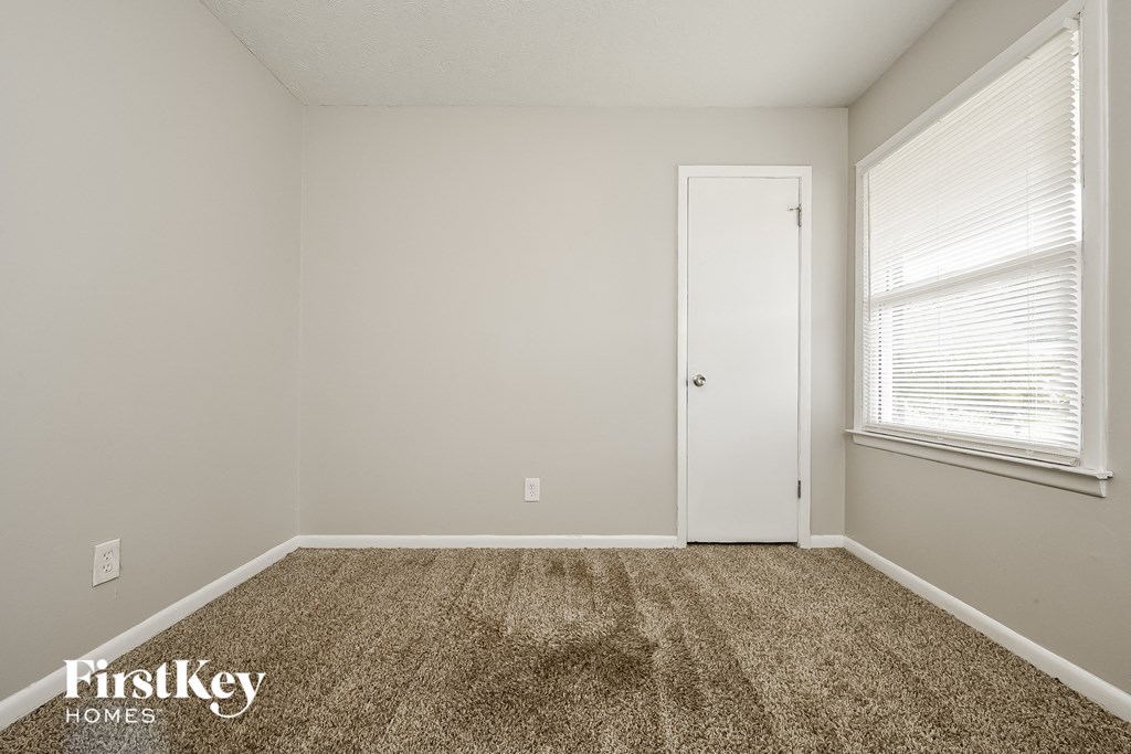 a room with a carpeted floor and a white door and a window