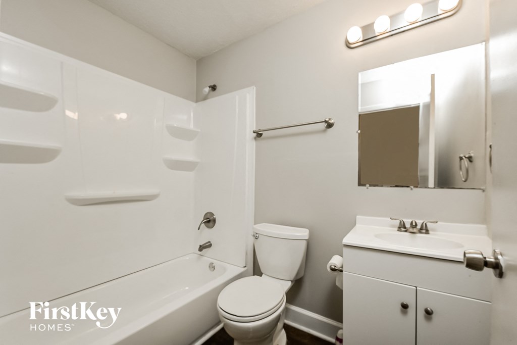 a bathroom with a toilet sink and tub and a mirror