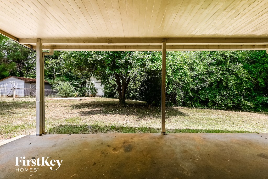 a covered porch in a backyard with trees